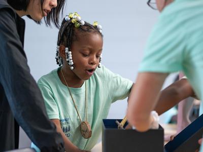 A Summer of Success student feels into a Mystery Box to describe the texture of the content. (Photo by Noah Allard) 